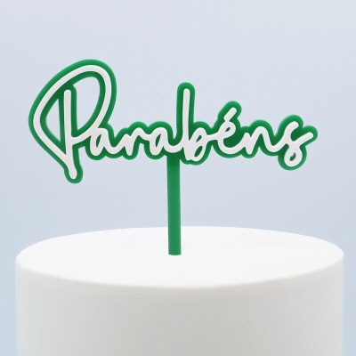 Topo de bolo verde com a palavra 'Parabéns' em bolo branco