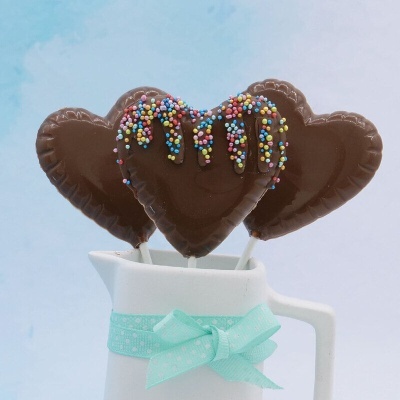 Pirulitos de chocolate em forma de coração num jarro branco com laço azul claro