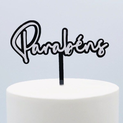 Topo de bolo preto com a palavra 'Parabéns' em letra cursiva sobre bolo branco