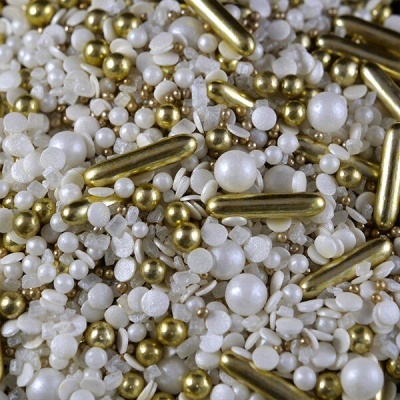 Mistura de esferas decorativas douradas e pérolas brancas em fundo branco.