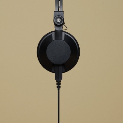 Auricular preto com cabo ligado sobre fundo bege