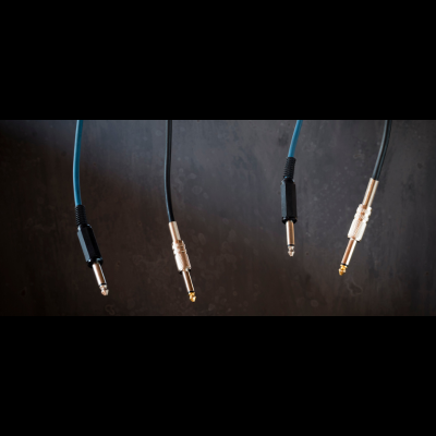 Quatro cabos de áudio com conectores P10 em fundo escuro