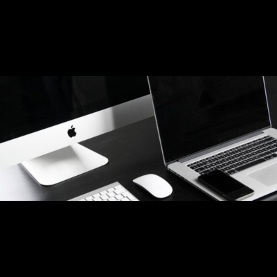 Computador iMac, teclado, rato e portátil Apple numa secretária