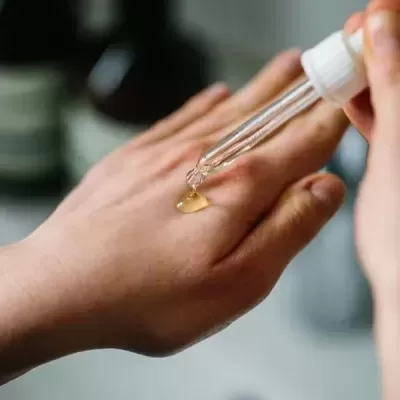 Mão a receber líquido amarelado com conta-gotas