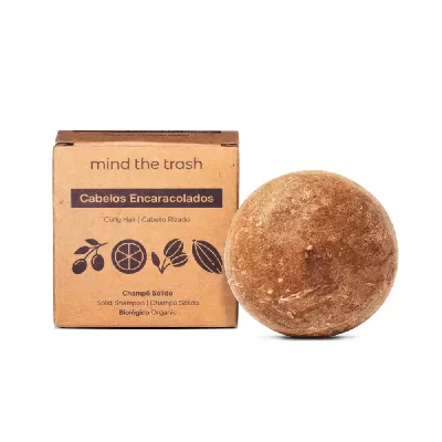 Champô sólido castanho redondo ao lado de embalagem de cartão castanho para cabelos encaracolados