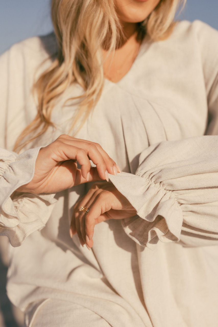 Blusa Serena Mulher loira com blusa creme de mangas franzidas