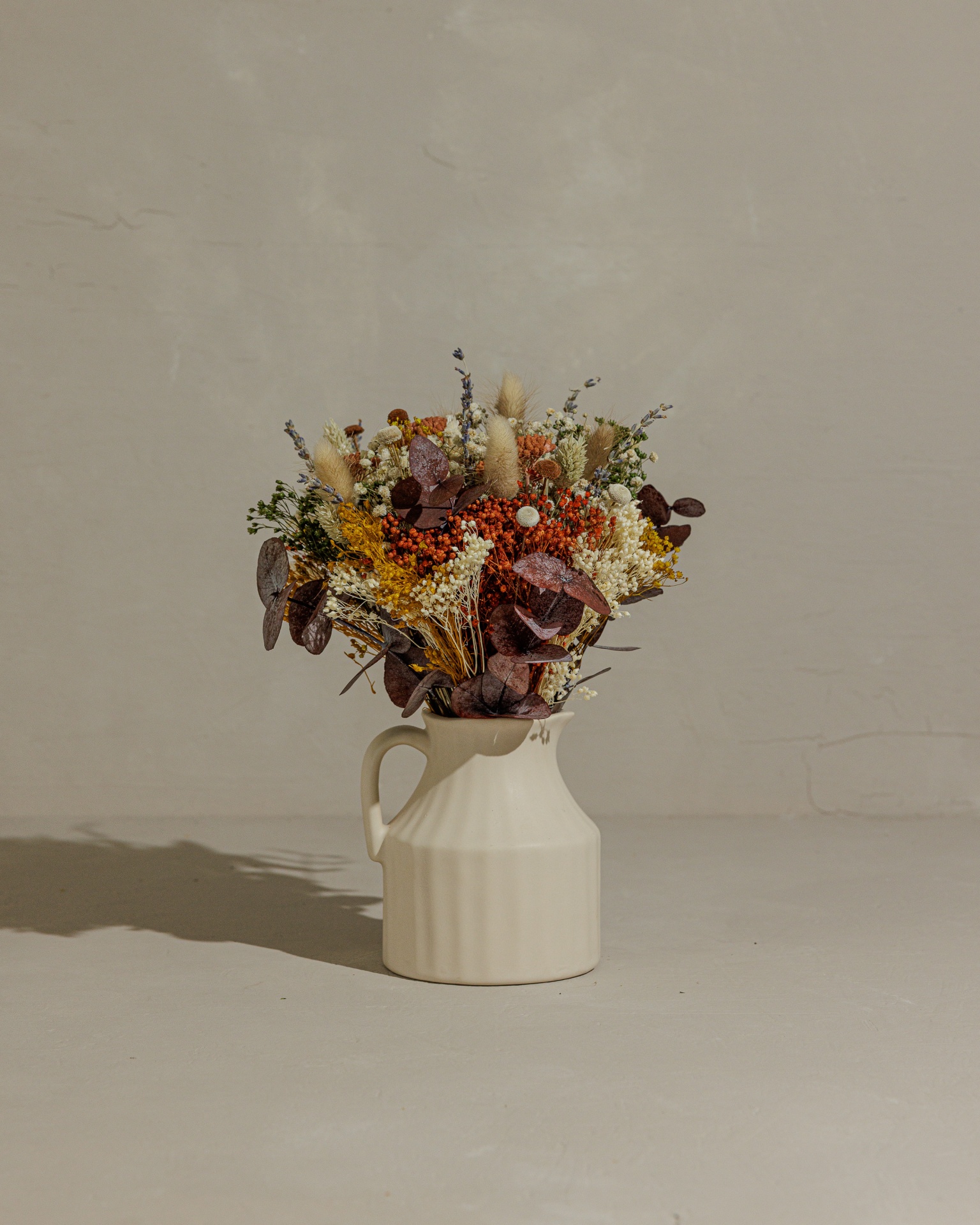 Jarro de mesa com ramo de flores Florescer Arranjo floral de flores secas em jarro branco de cerâmica sobre superfície cinzenta