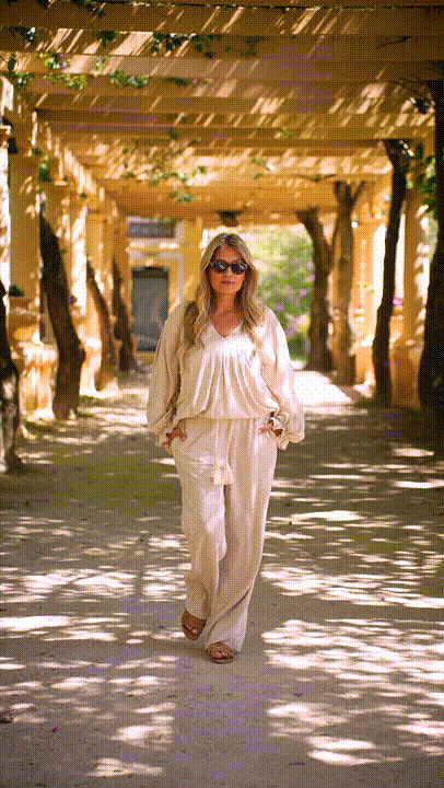 Blusa Serena Mulher com conjunto bege de camisa e calças largas e óculos de sol escuros a caminhar ao ar livre