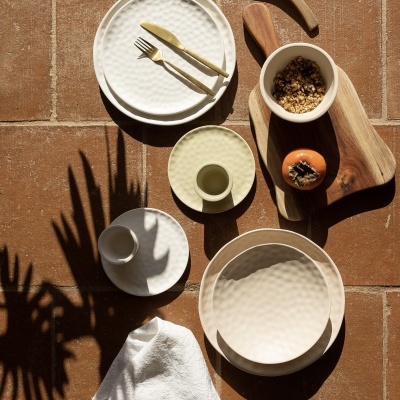 Conjunto de loiça cerâmica e utensílios de madeira sobre chão de tijoleira