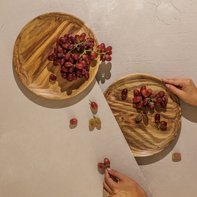 Duass tábuas redondas de madeira com uvas roxas sobre superfície cinza