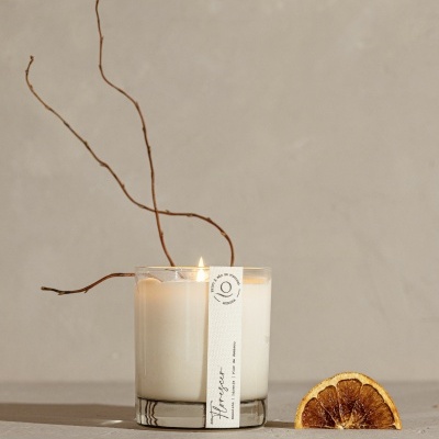 Vela em copo transparente com rótulo e laranja seca ao lado