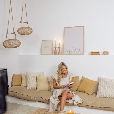 Sofá com almofadas neutras, cestas penduradas e mesa de centro rústica com vela