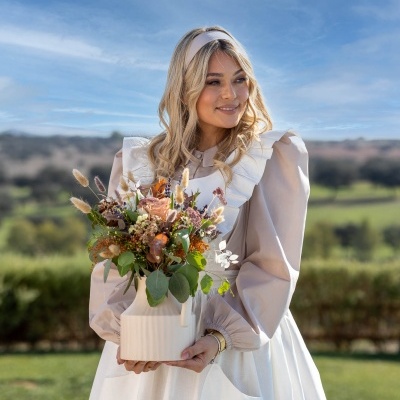 Mulher segurando vaso branco com flores secas ao ar livre