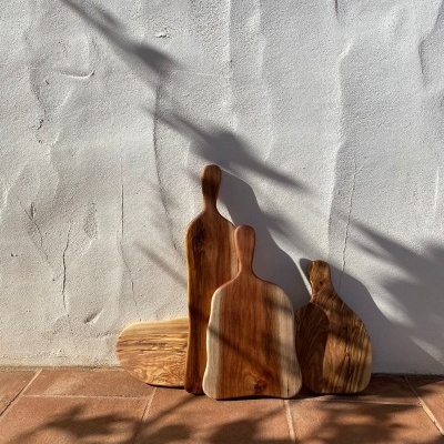 Três tábuas de madeira para corte em diferentes tamanhos apoiadas numa parede branca