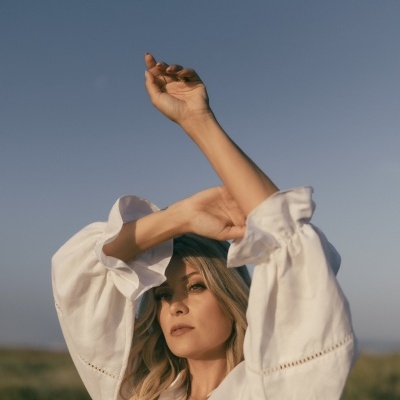 Mulher com camisa branca de tecido leve em ambiente exterior