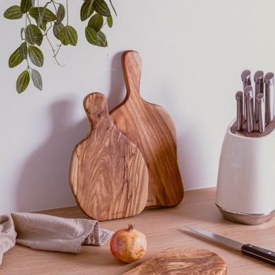 Tábuas de cortar em madeira, faca, aparelho de facas branco e romã numa mesa de madeira