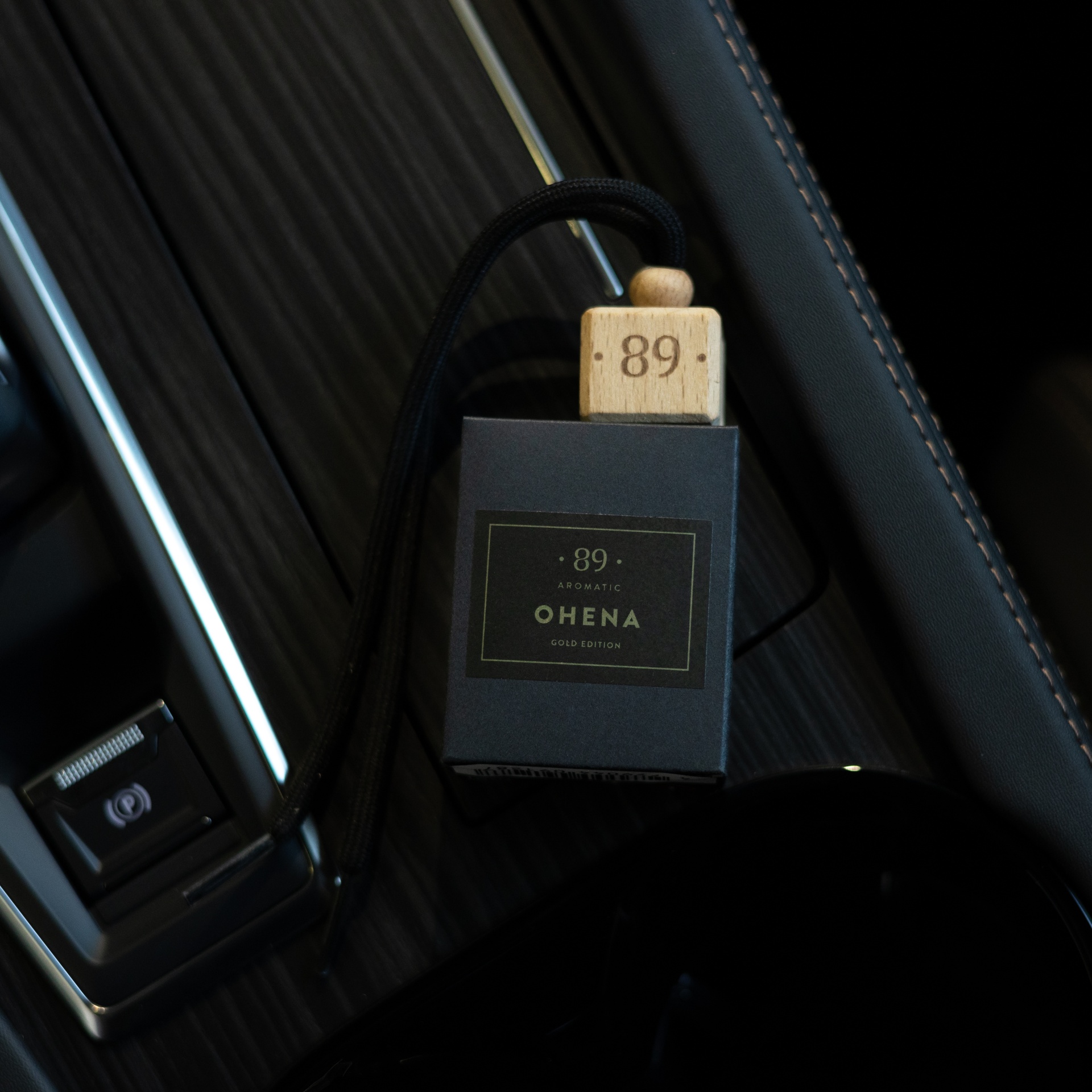 Frasco aromático preto com tampa de madeira e cordão sobre superfície preta texturizada