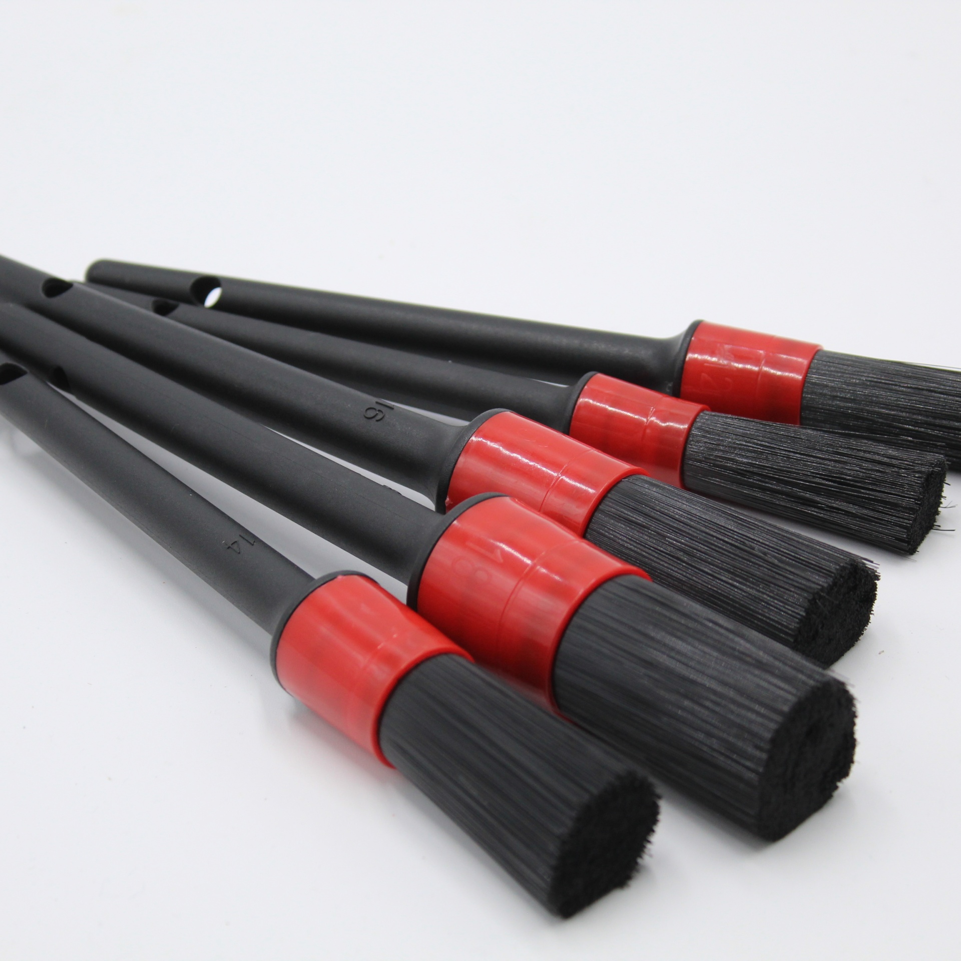 Conjunto de cinco pincéis com cabos pretos e detalhes vermelhos