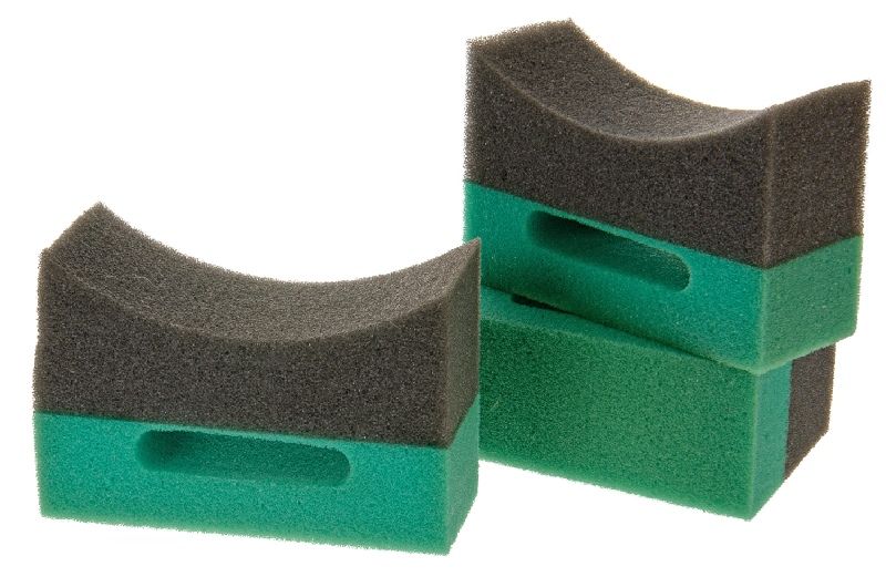 Duas esponjas de limpeza preta e verde com formato curvado e orifício central.