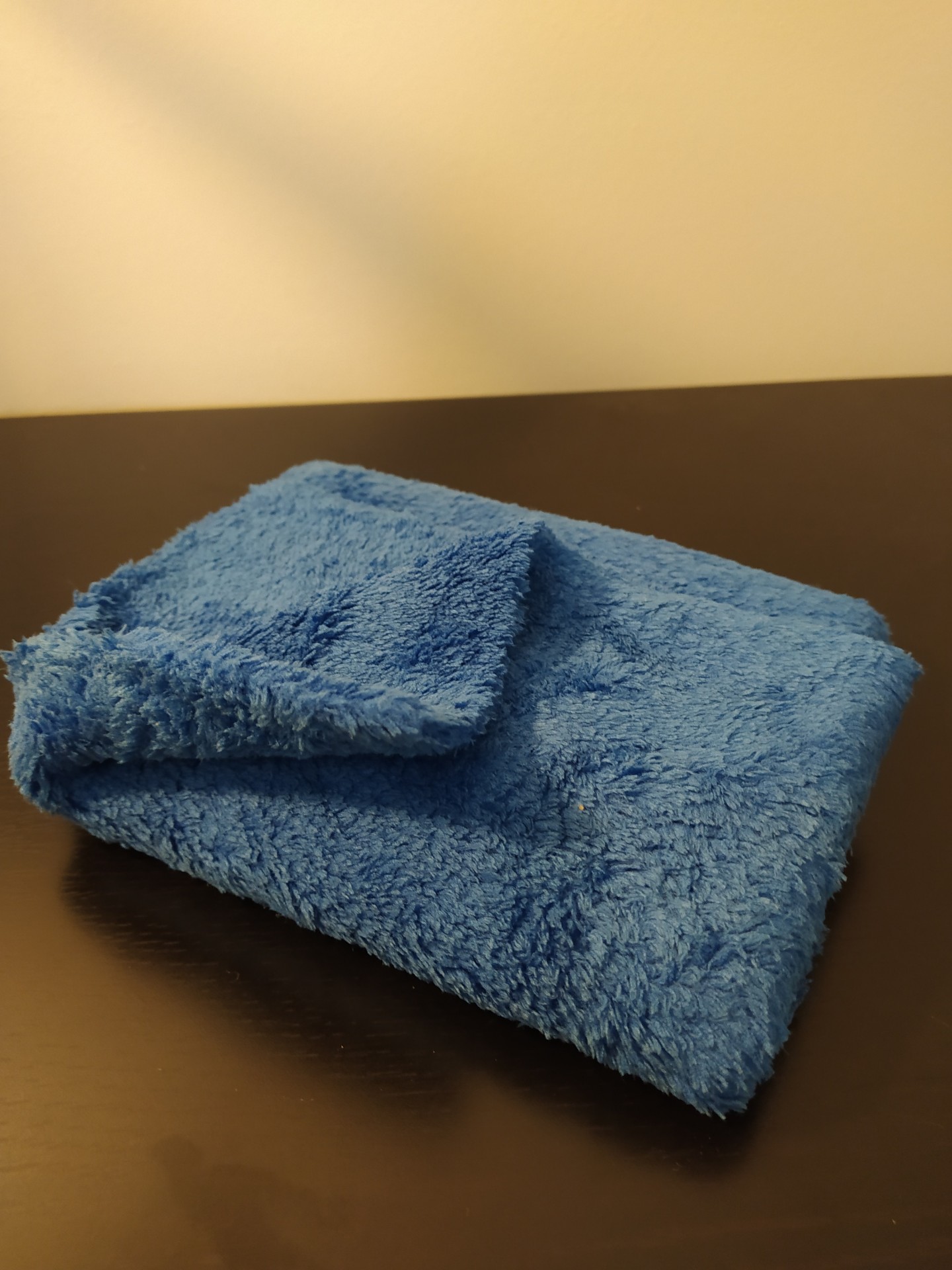 Toalha azul macia dobrada sobre superfície escura