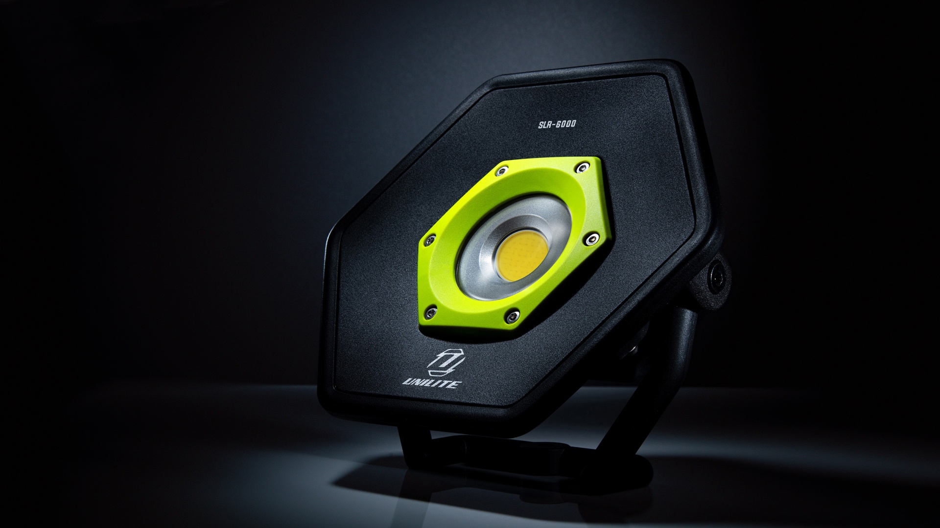 Coluna de som preta e amarela em suporte sobre fundo escuro