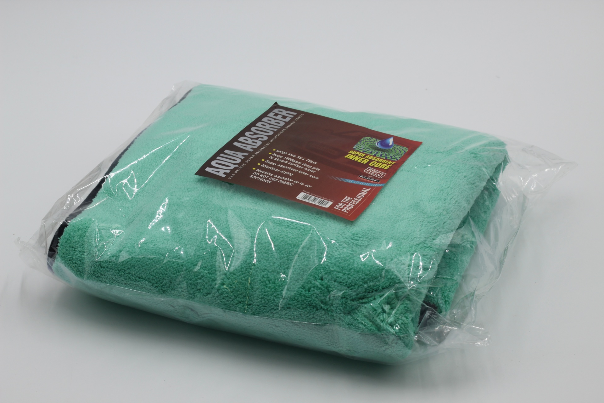 Toalha verde água embalada em plástico transparente com etiqueta preta e castanha