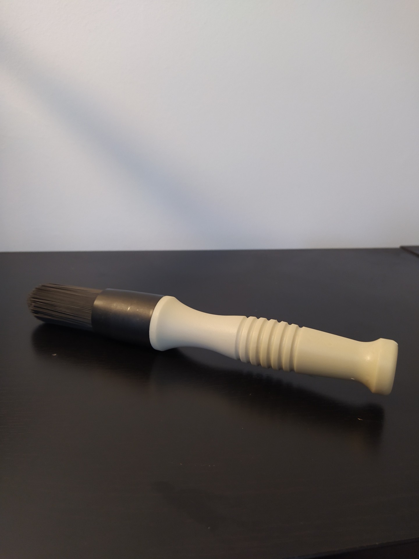 Pincel com cabo bege e cerdas pretas numa superfície preta