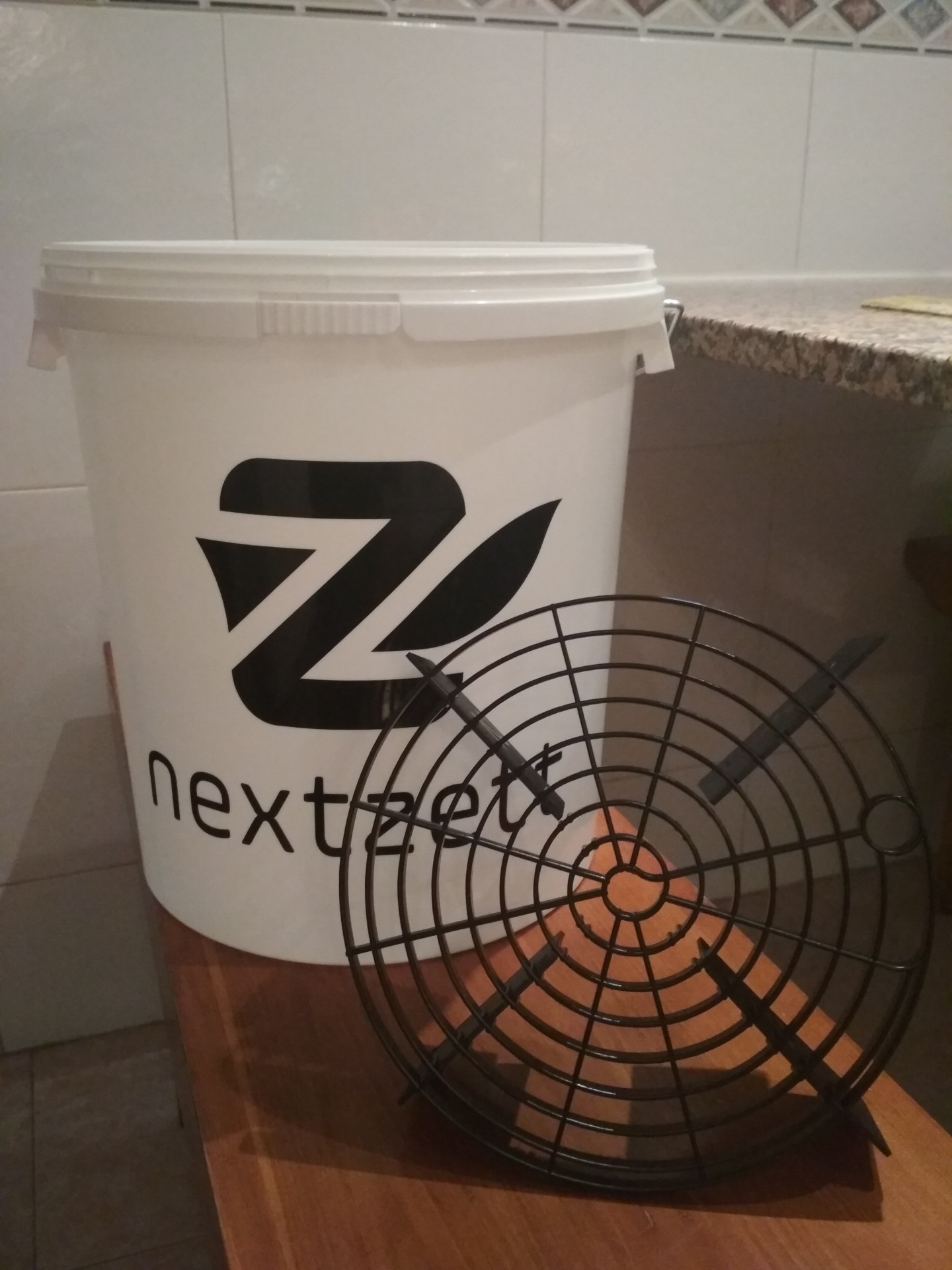 Baldes brancos com logótipo nextzett e grelha preta numa cozinha