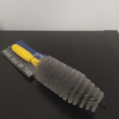 Escova de limpeza com cabo amarelo e cerdas cinzentas sobre superfície preta