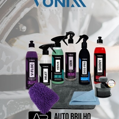 Produtos de limpeza automóvel Vonixx com spray, frascos líquidos, luva de microfibra roxa, pano azul e escova preta sobre almofada cinzenta.