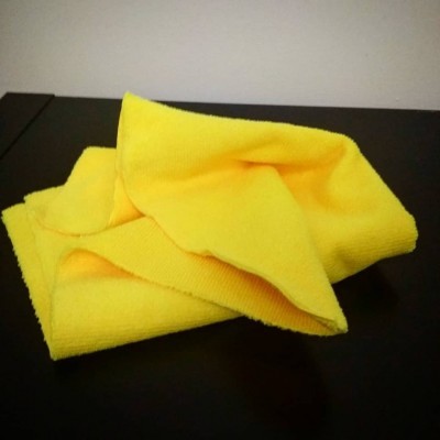 Toalha de microfibra amarela dobrada sobre superfície preta