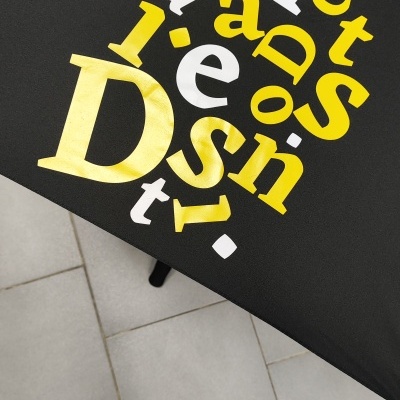 Guarda-chuva preto com letras amarelas e brancas formando 'Soft Design'