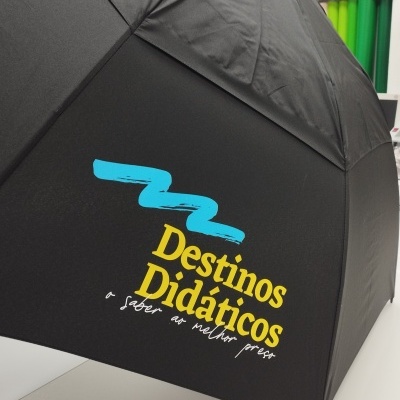 Guarda-chuva preto com texto colorido e rolos coloridos ao fundo