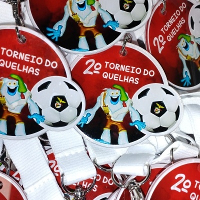 Medalhas vermelhas do 2º Torneio do Quelhas com personagem azul e bola de futebol.