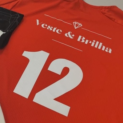 Camisola desportiva vermelha alaranjada com número 12 branco e texto Veste & Brilha