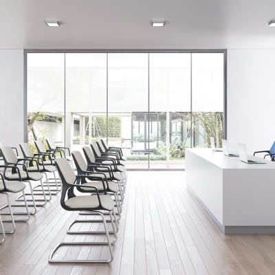 Sala de conferências com cadeiras bege e azuis junto a mesa branca