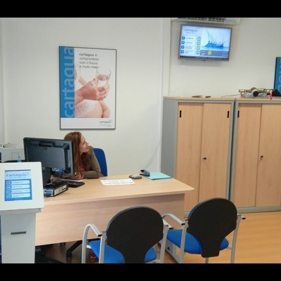 Escritório contém secretária, cadeiras, armários e cartaz na parede