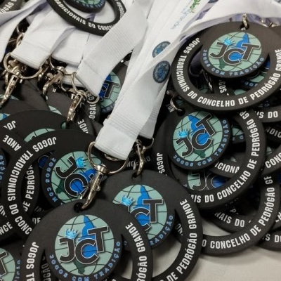 Medalhões redondos pretos com fitas brancas e logótipos coloridos