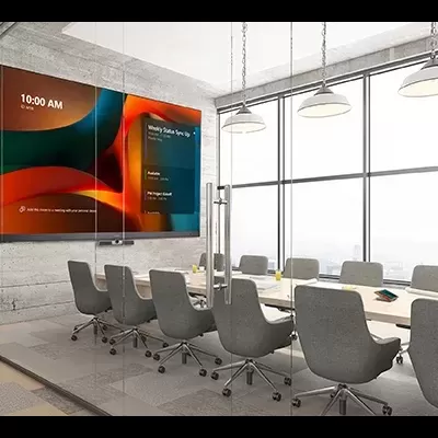 Sala de reuniões moderna com mesa branca e cadeiras cinzentas, telas na parede com texto, iluminação pendente e vista urbana