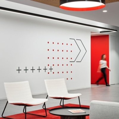 Sala moderna com cadeiras brancas, mesa preta, tapete vermelho e decoração geométrica na parede