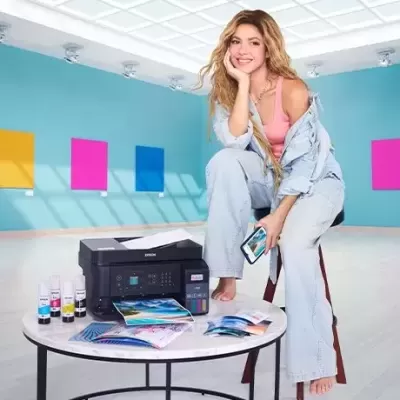 Mulher sentada numa mesa com impressora e tinta em sala moderna