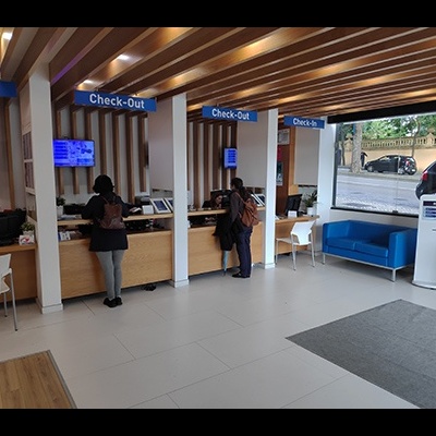 Balcão de Check-In e Check-Out em espaço claro com pessoas e sofá azul