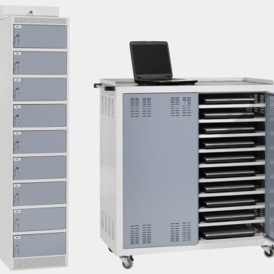 Armário alto branco com portas cinzentas e carrinho cinzento com gavetas e computadores portáteis