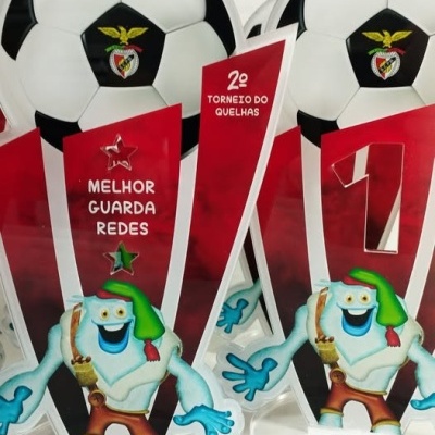 Troféus de futebol com bola, logótipo do Benfica, e texto 