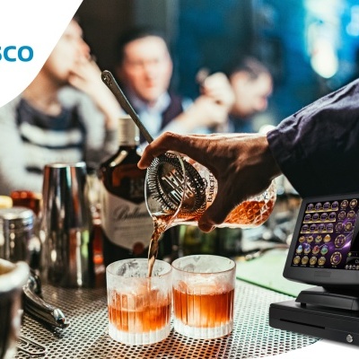 Máquina registadora preta com ecrã digital num balcão metálico enquanto uma bebida é servida em copos