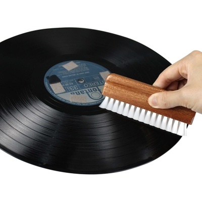 Disco de vinil preto a ser limpo com escova de madeira e cerdas brancas