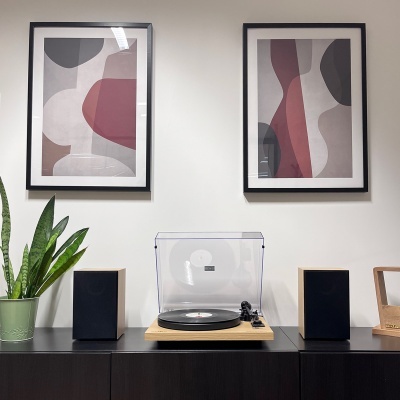 Gira-discos com altifalantes, planta e quadros abstratos na parede