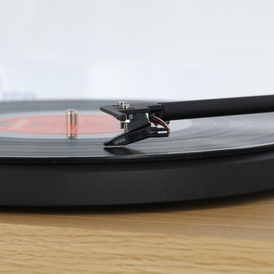 Gira-discos preto a tocar disco de vinil transparente numa superfície de madeira