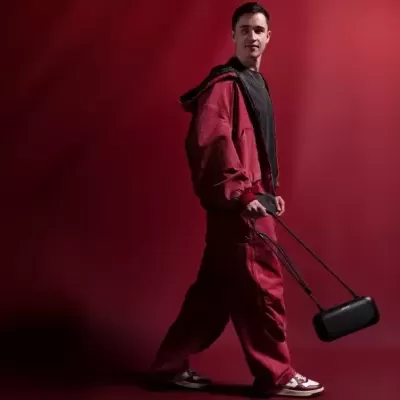 Homem com fato de treino vermelho e bolsa preta num fundo vermelho