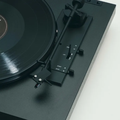 Gira-discos preto com vinil e texto branco no braço de leitura